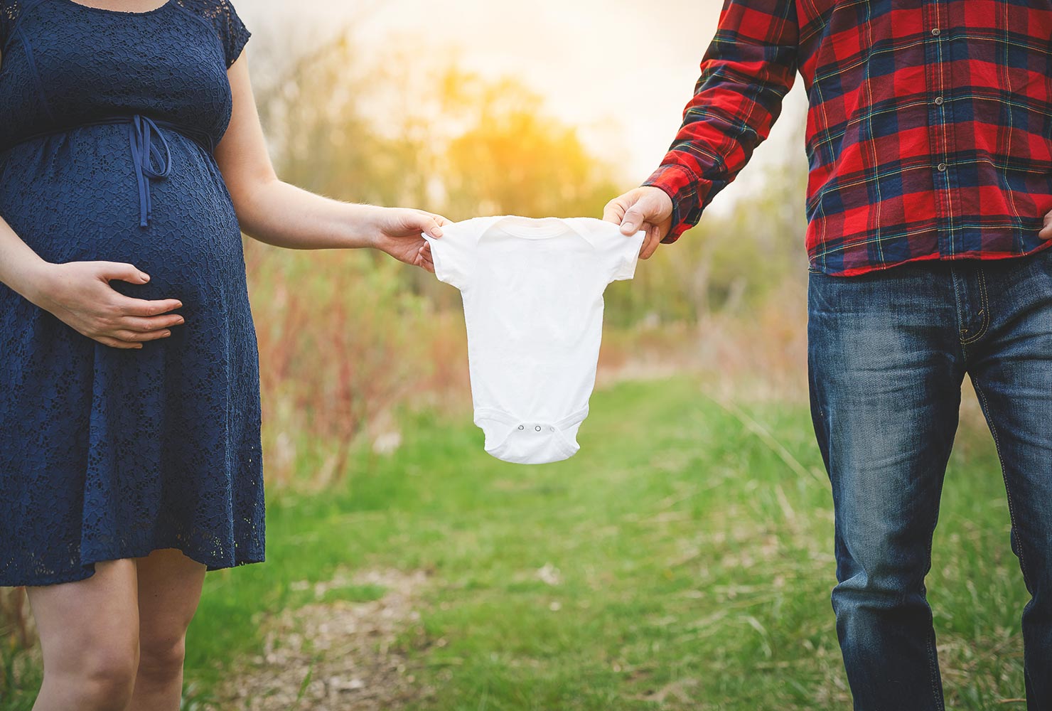 caucasian- couple holding up neutral gender onesie