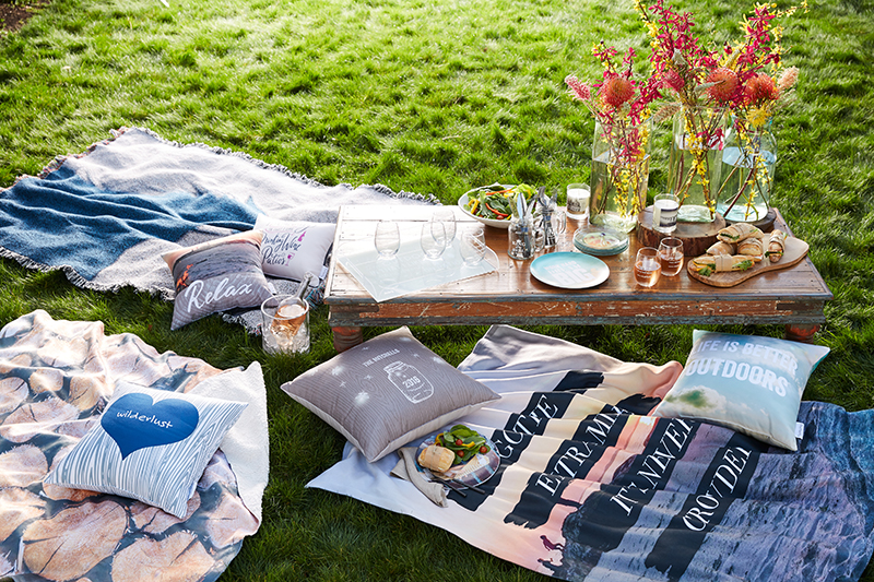 Summer party spread for backyard featuring personalized blankets and custom pillows