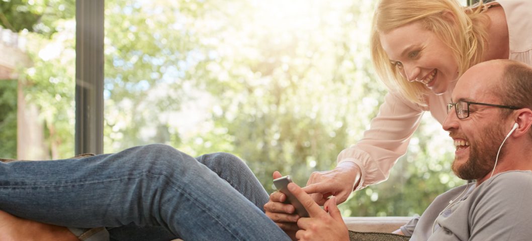 Couple at home using digital tablet to upload video to Shutterfly.