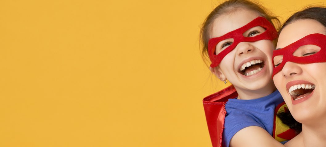 Mother and her child playing together in Superhero costumes.