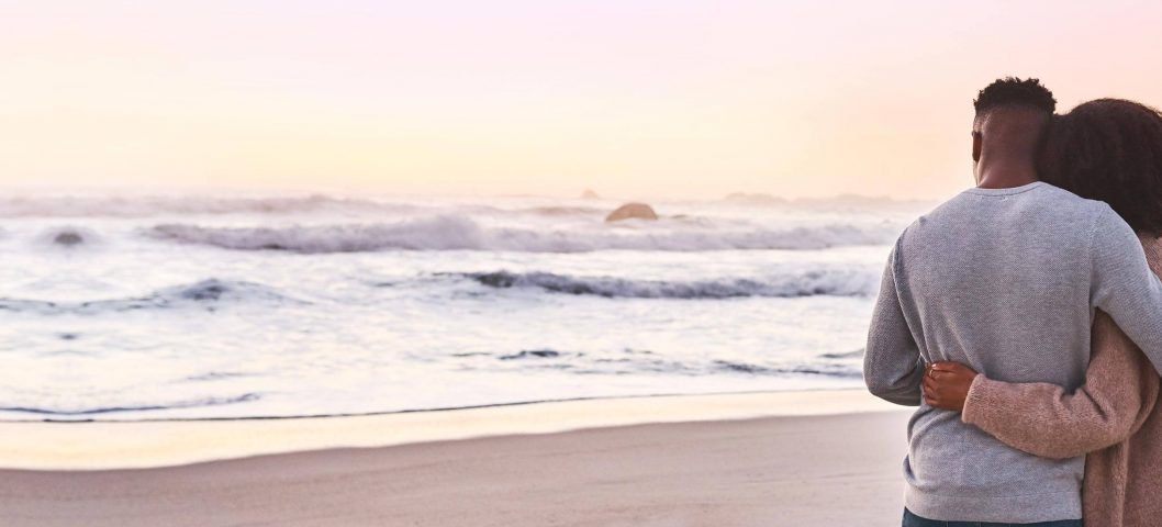 Couple hugging while looking at ocean.