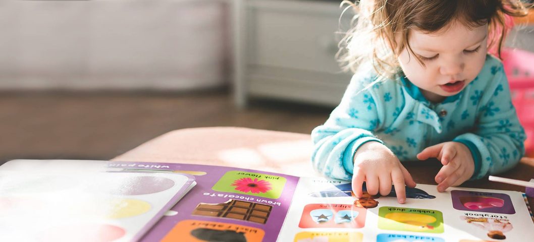 Baby girl looking at picture book.