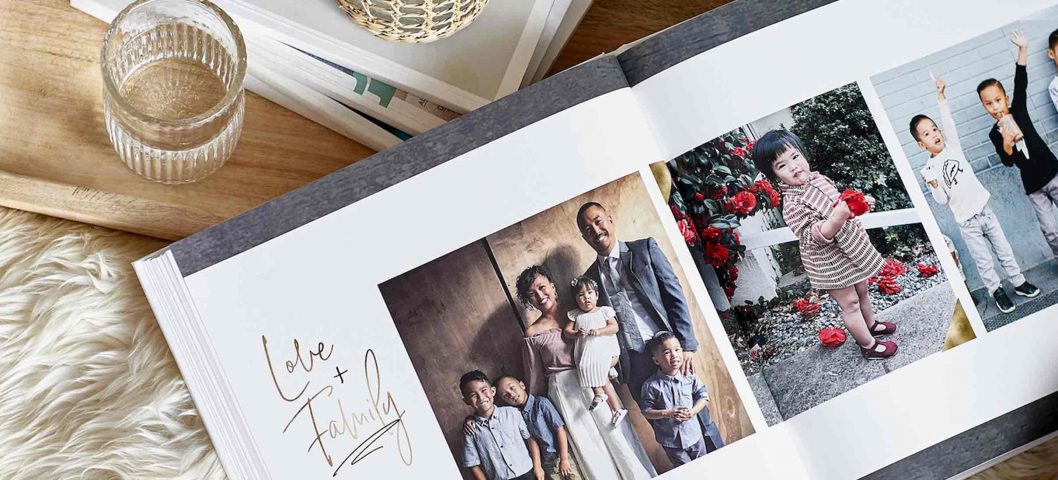 Photo book open on coffee table next to stack of books.