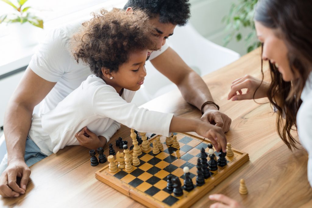 Happy family playing chess together at their home