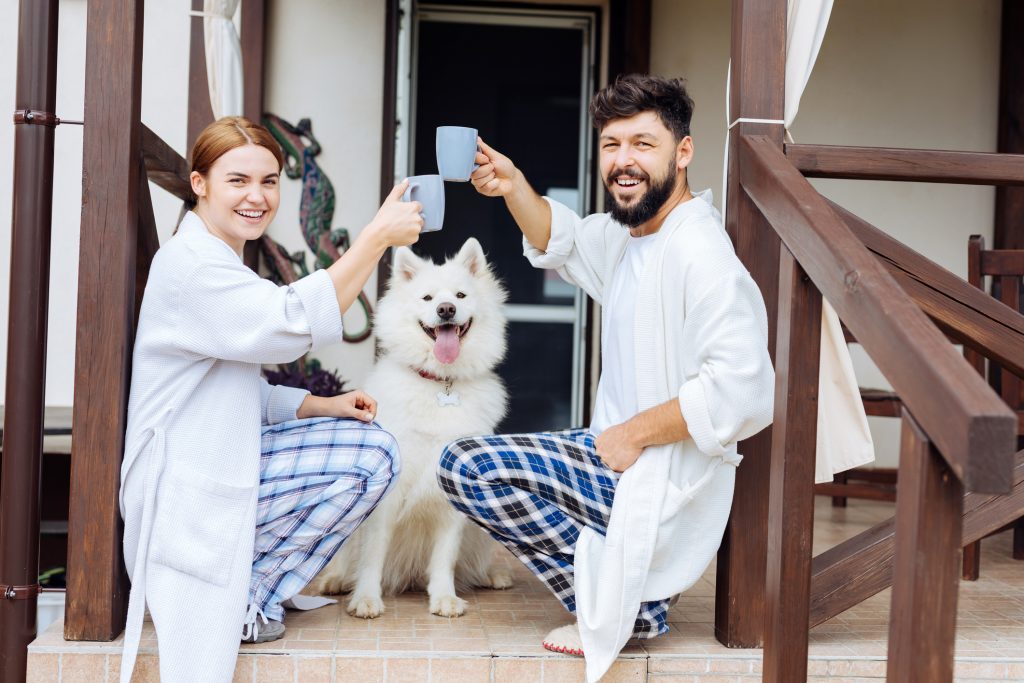 Smiling wife and husband drinking tea on their front porch