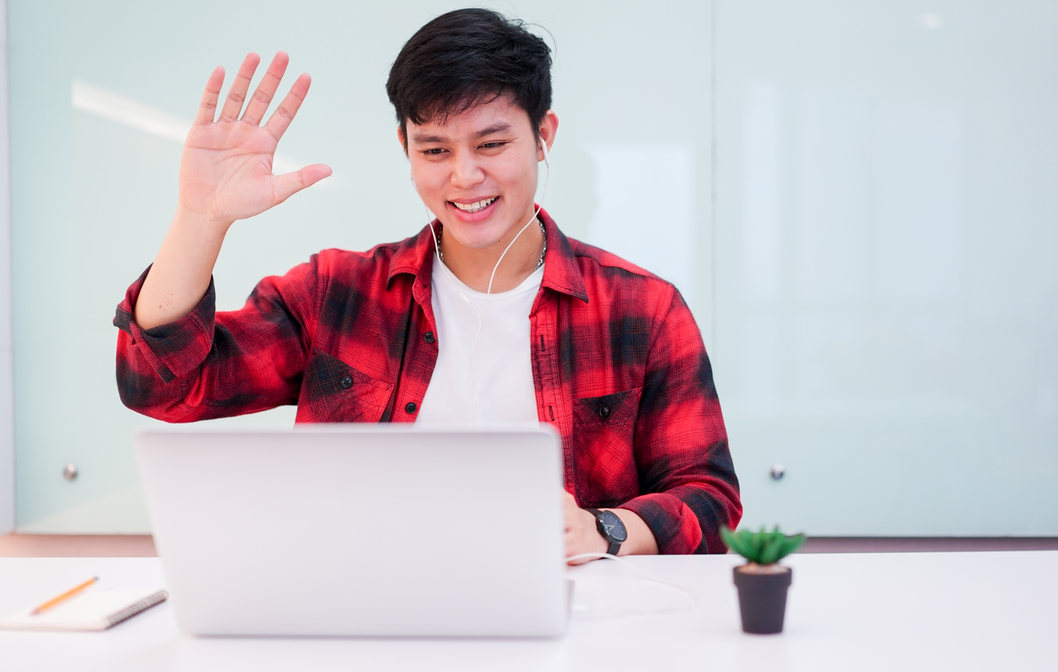 young man wearing earphone and greeting on video conference 