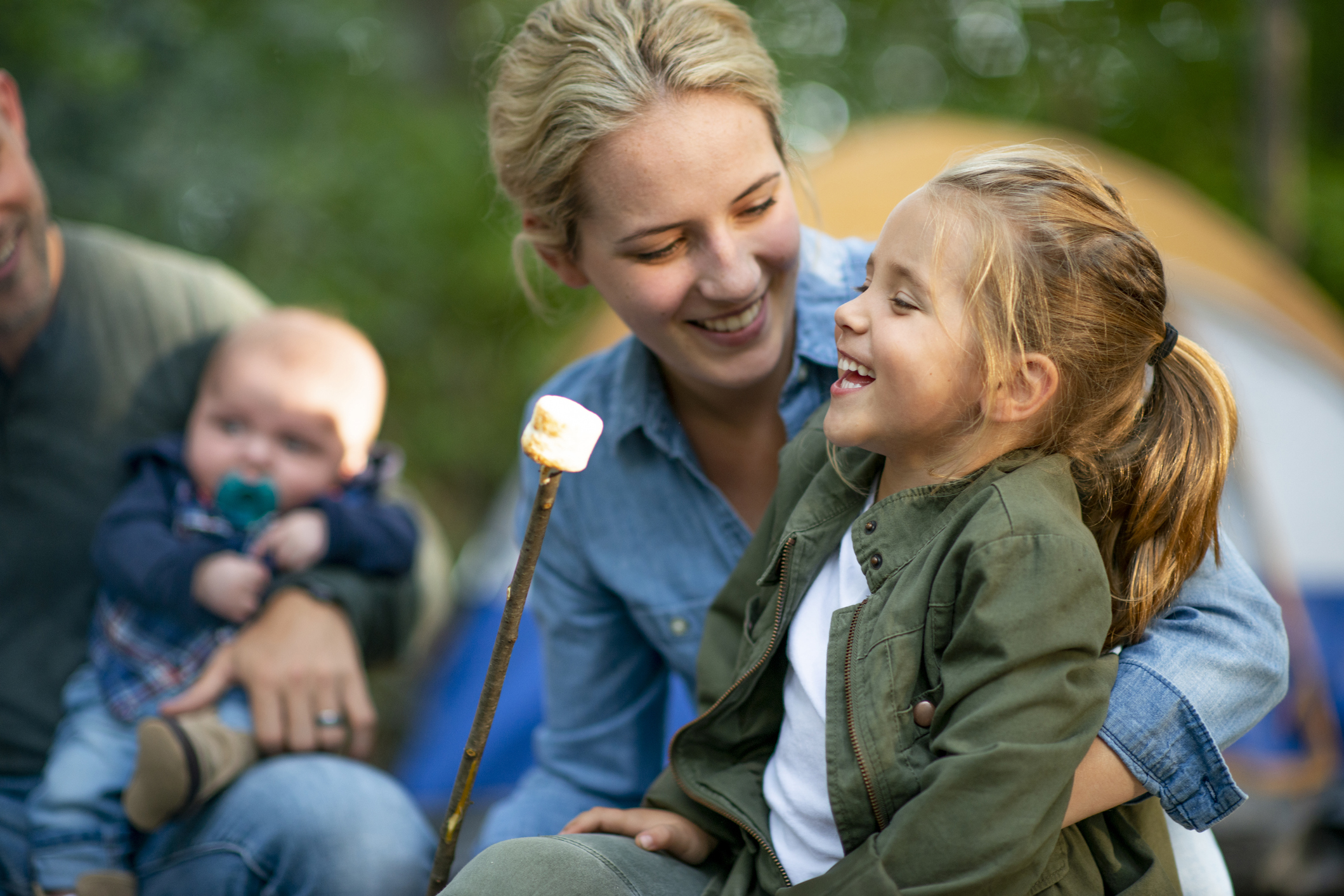 family roasting marshmallows at a camping themed summer camp at home