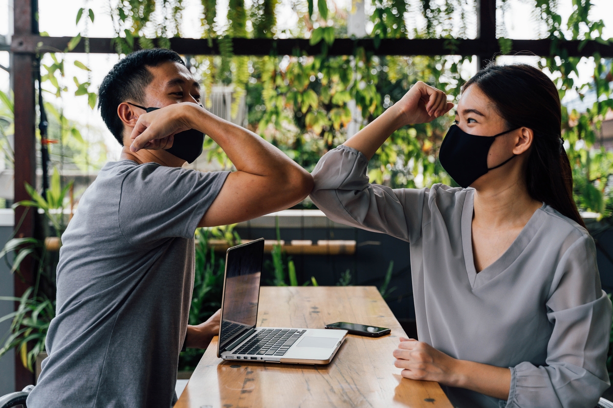woman and man friends wearing face mask outdoors. Friends greeting and shaking with elbows as new normal. Corona Virus - Covid 19 elbow bumps greeting style to prevent contact and virus spread