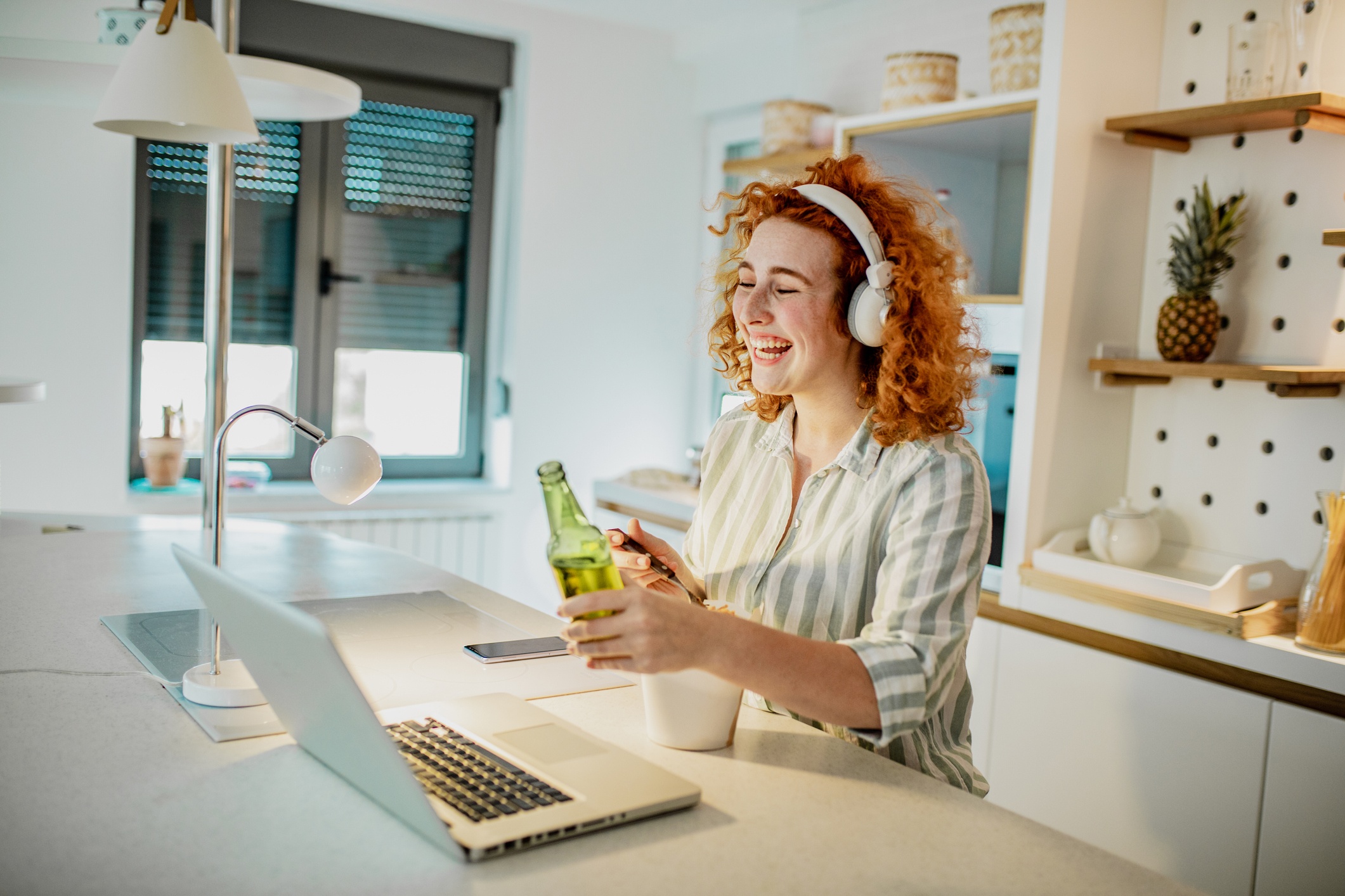 young woman in kitchen having a virtual happy hour with work team