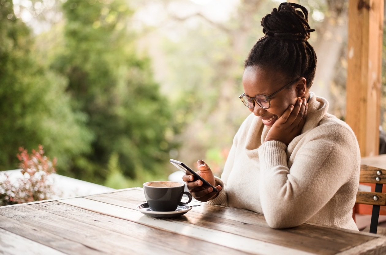 woman looking at her phone and smiling while reading a text message