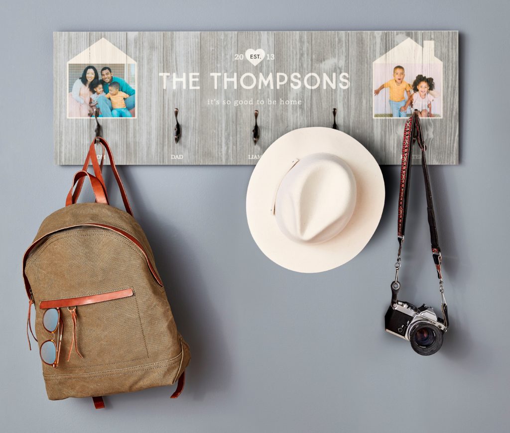 Wall hook organizers with family name and backpack hat and camera on the hooks with family pictures