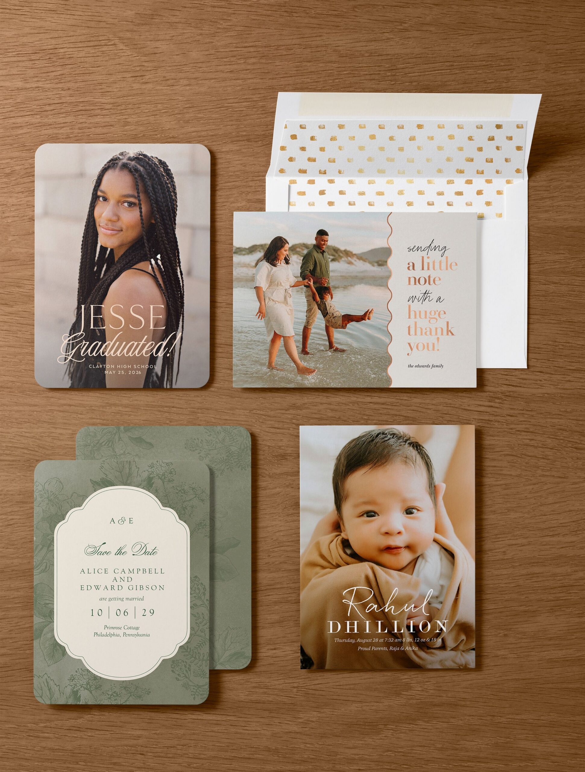A flat lay of personalized announcement and invitation cards, including a graduation announcement, thank‑you photo card, wedding invitation, and baby announcement, arranged on a warm wood surface with envelopes.