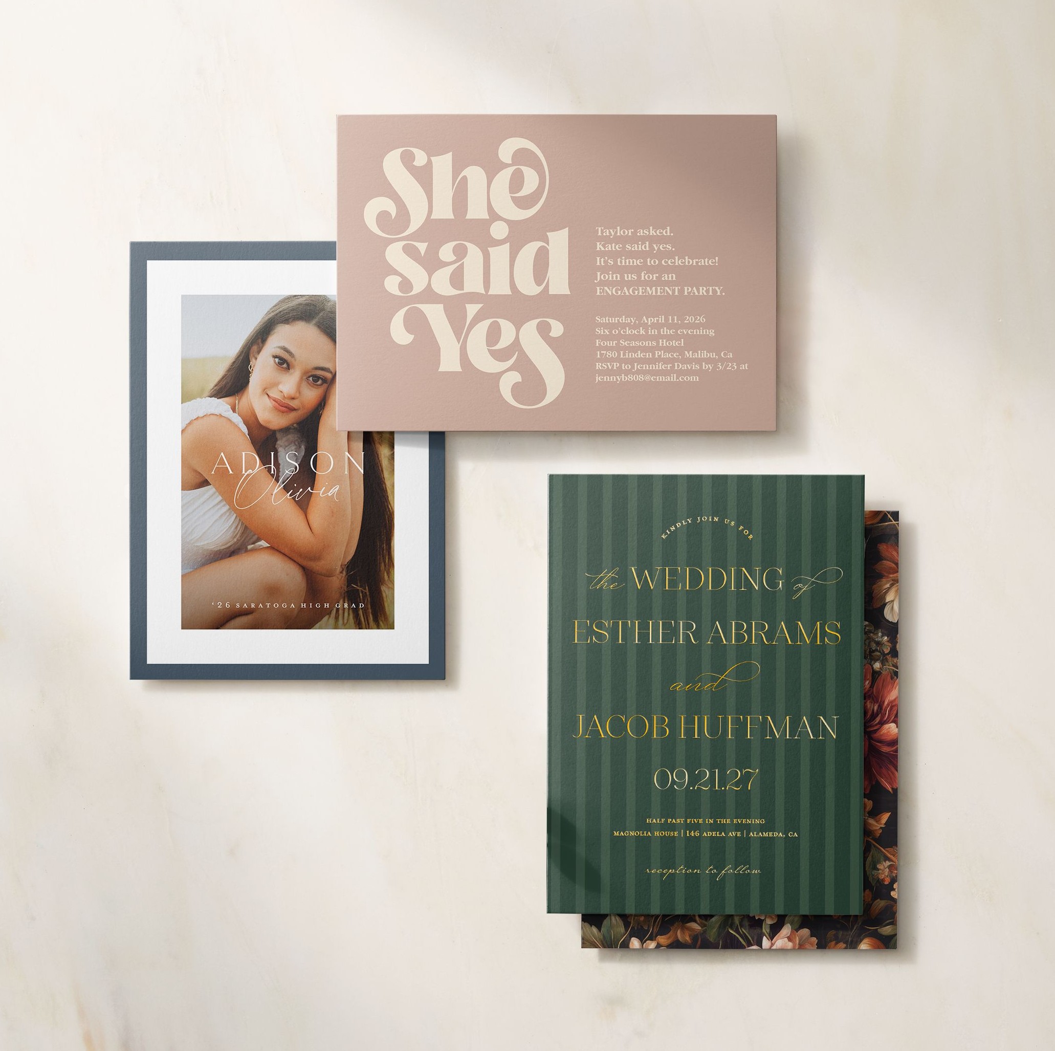 A flat lay of coordinated engagement and wedding stationery, including a photo card, “she said yes” engagement announcement, and formal wedding invitation arranged on a light neutral background.