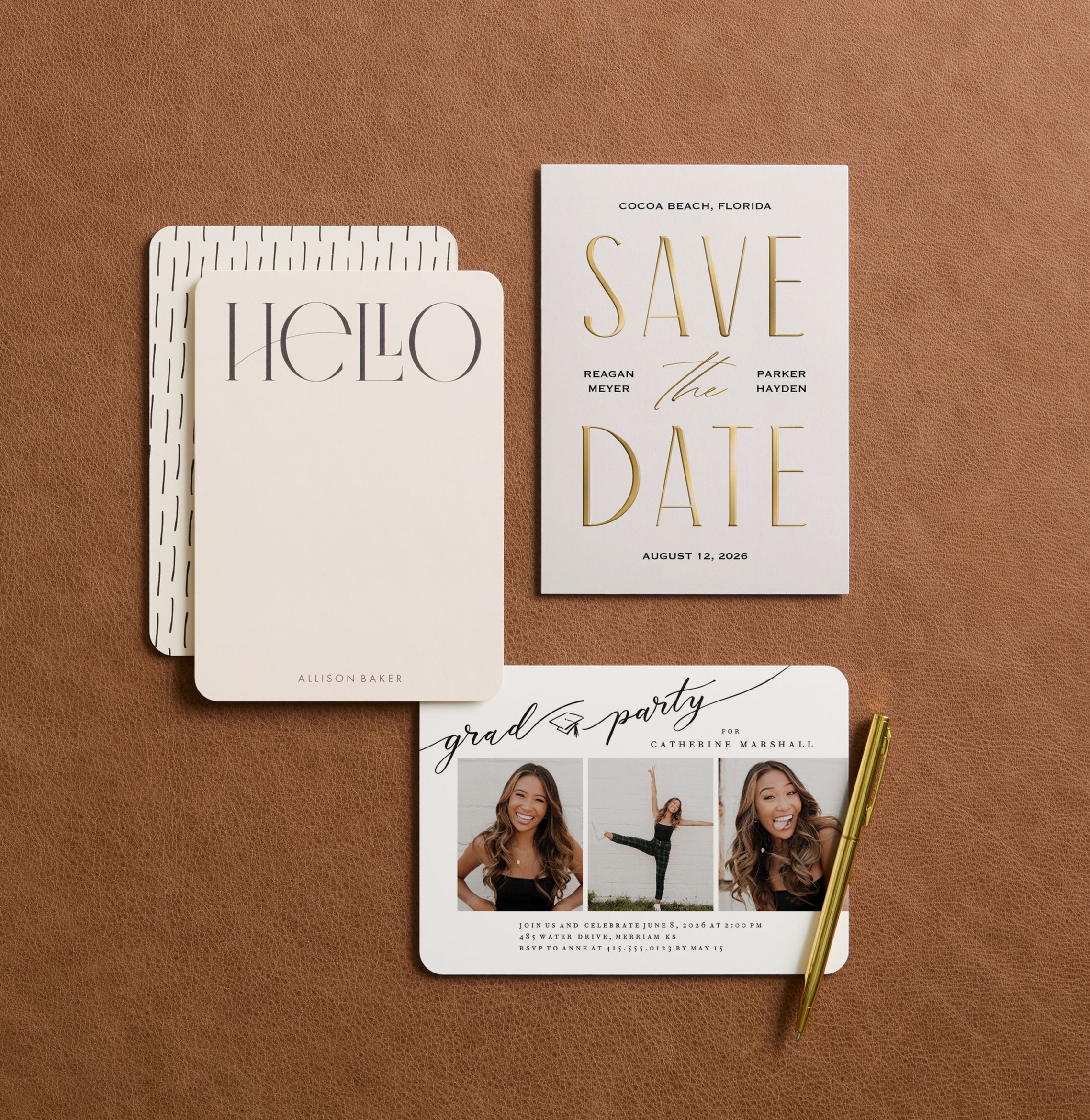 A flat lay arrangement of modern personalized stationery including a save the date card, greeting card, and graduation invitation with a pen displayed on a warm brown textured surface.