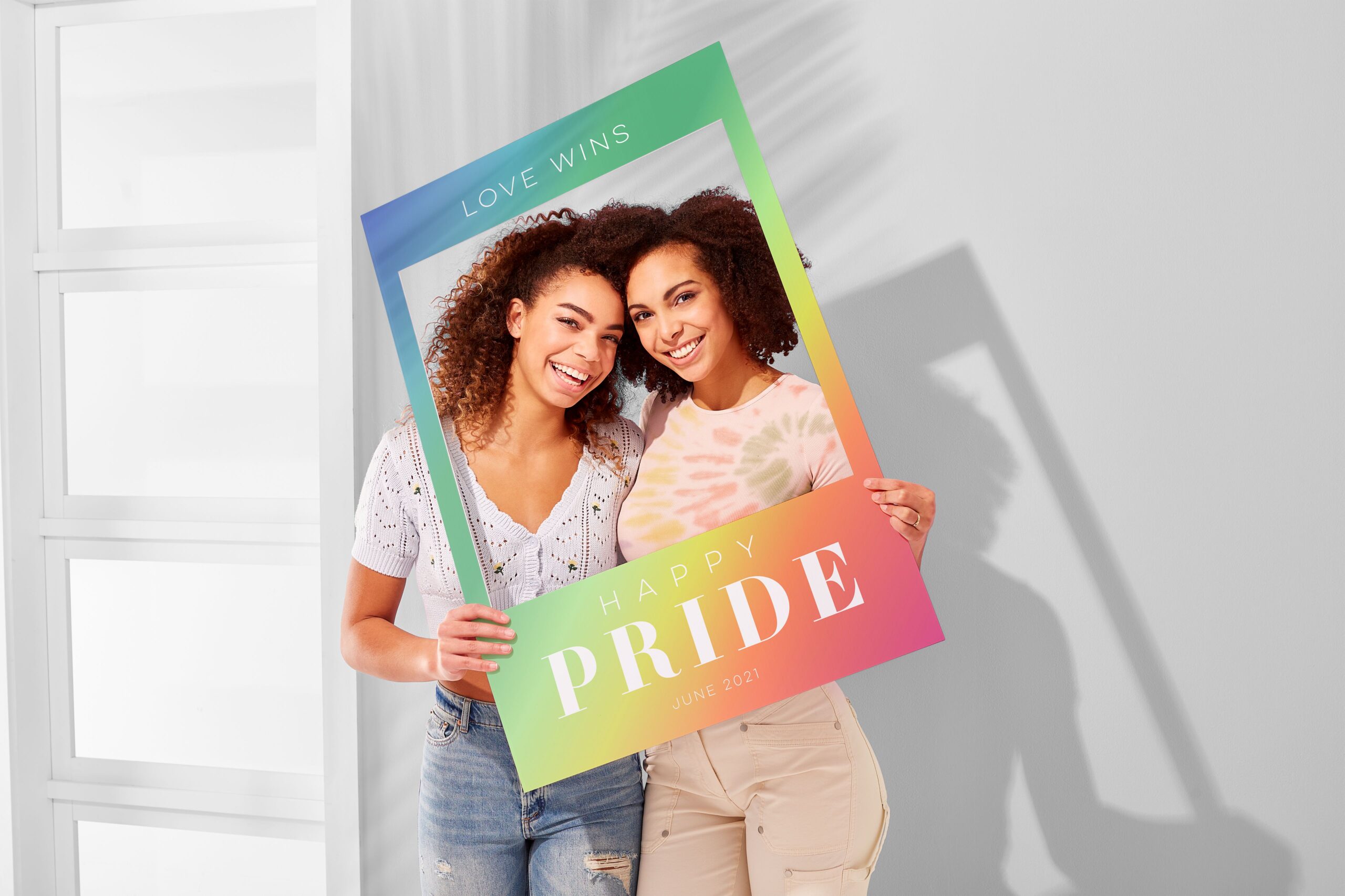 two girls posing with a pride selfie frame