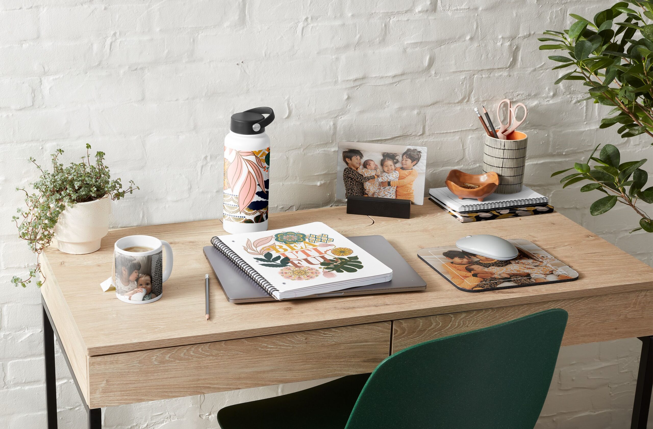 collection of office supplies like a note book, mouse pad, water bottle, coffee mug, and photo print