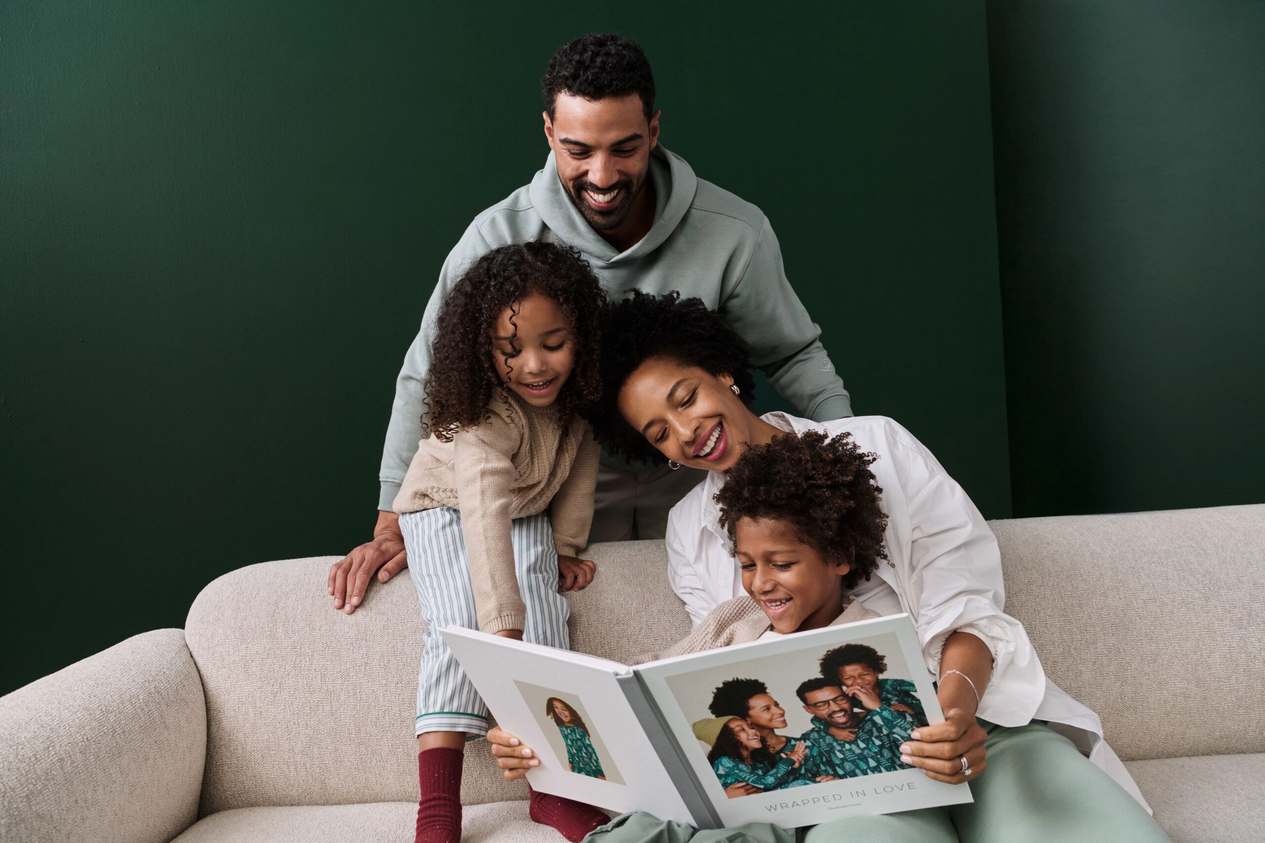 family looking at photo book together on a couch