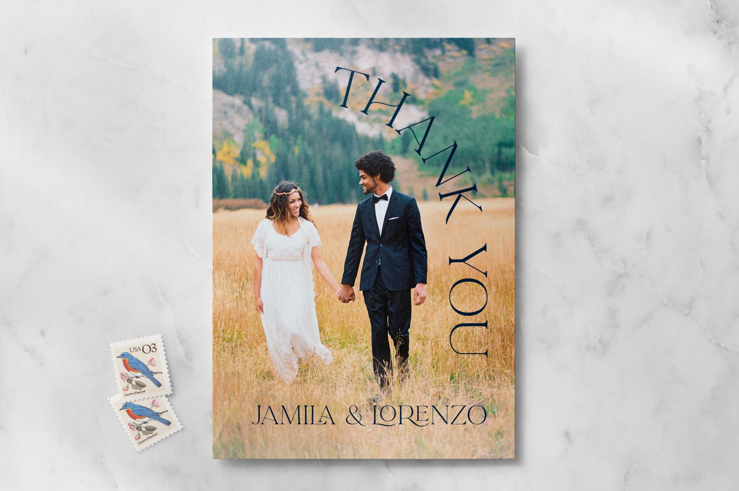 a photo wedding thank you card next to two stamps
