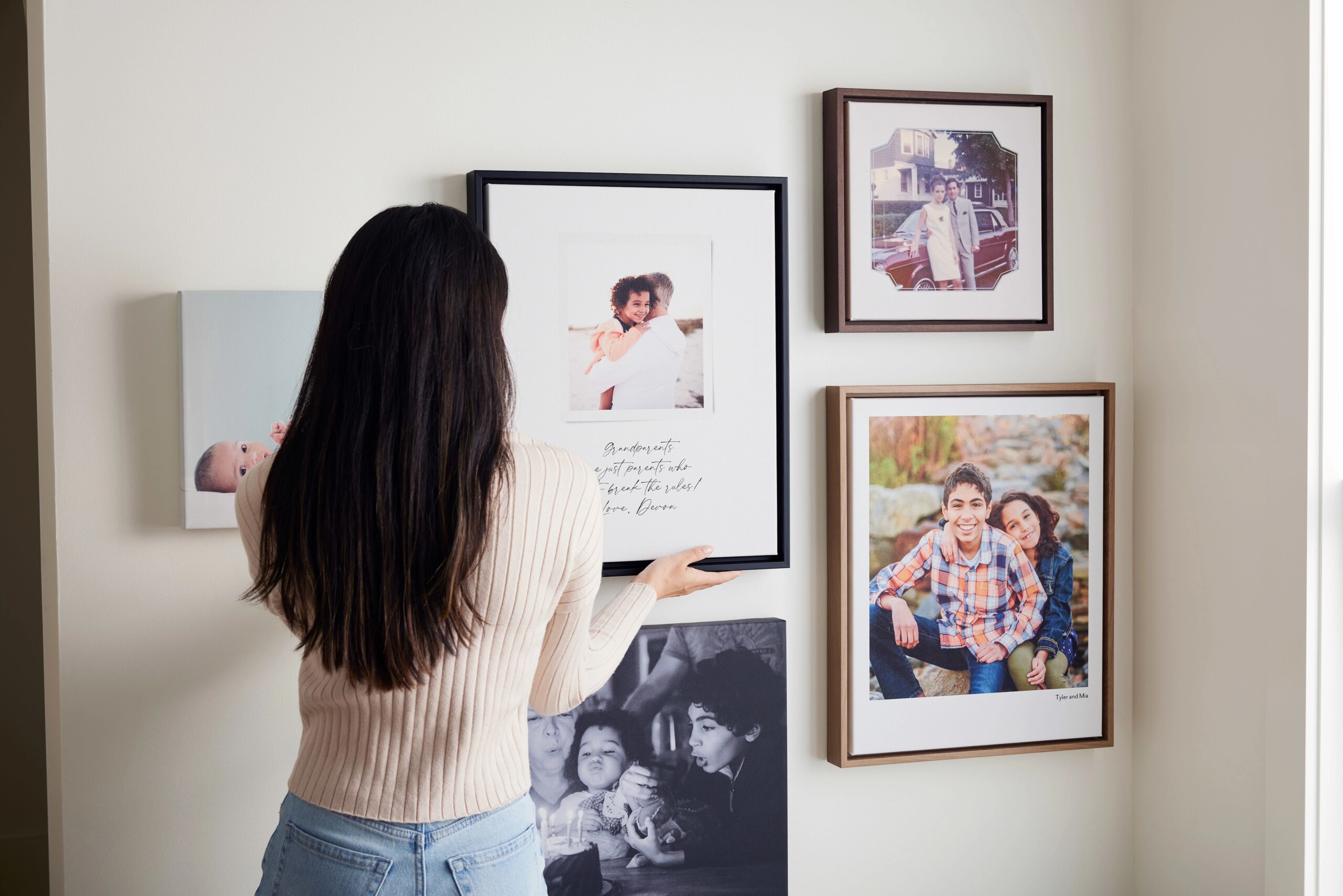 woman hanging framed canvas prints on a wall