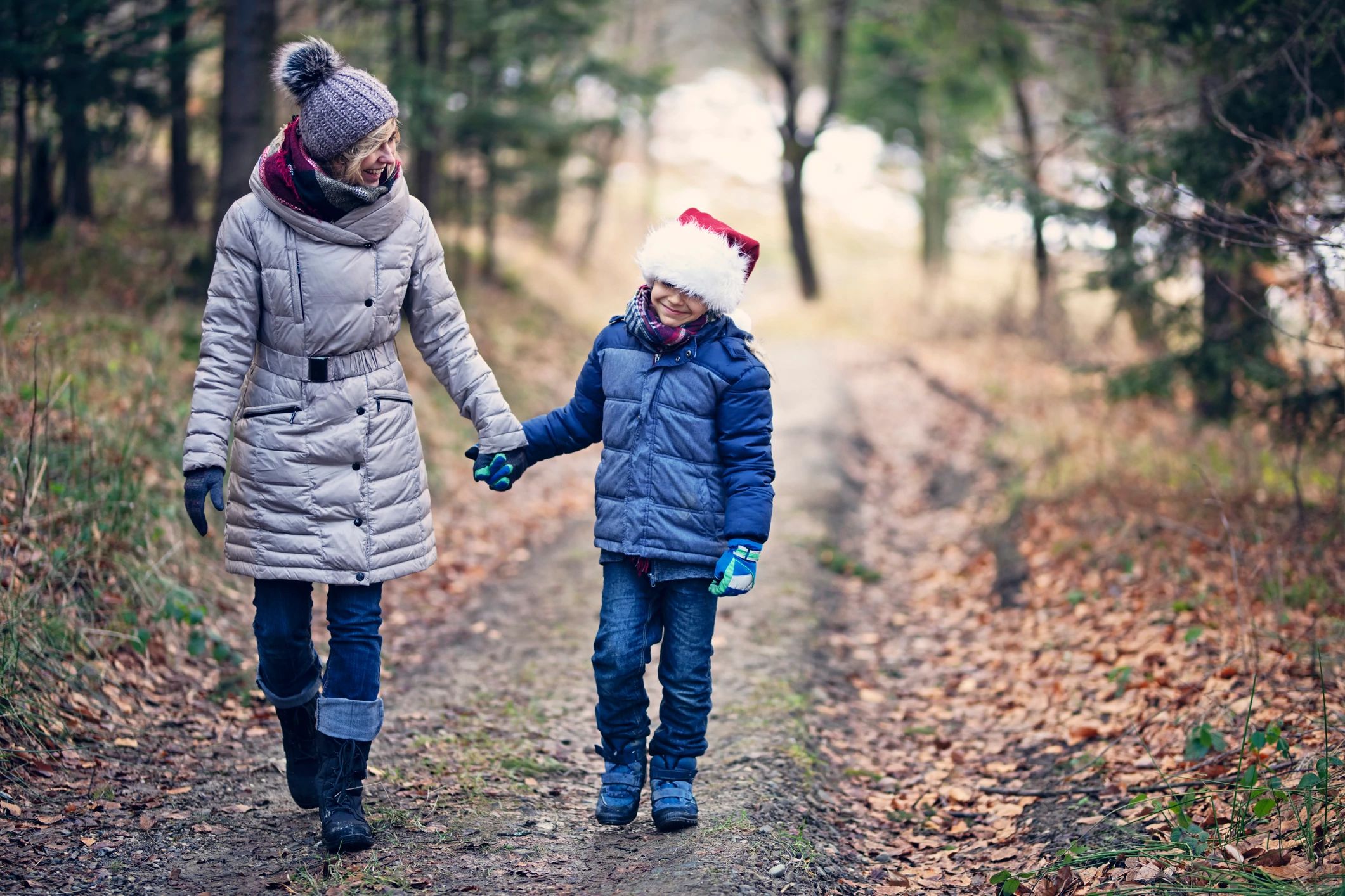 mom and child walking outside with a santa hat on