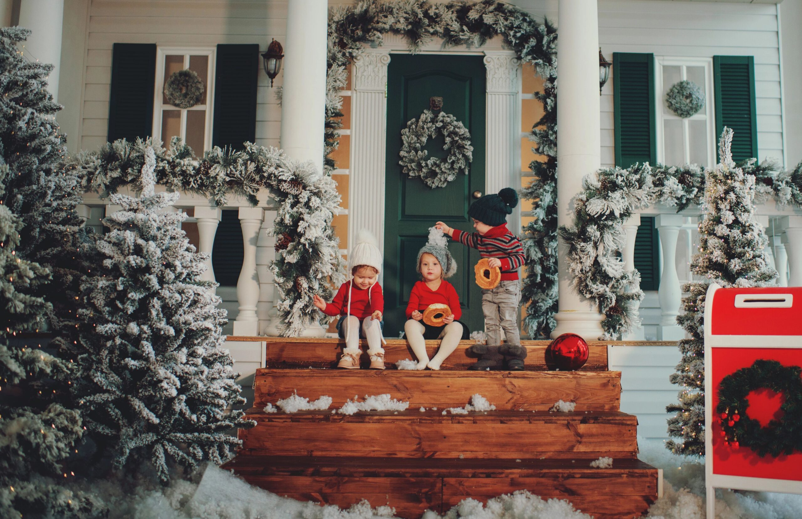 children posing in the snow for a christmas photo on the porch