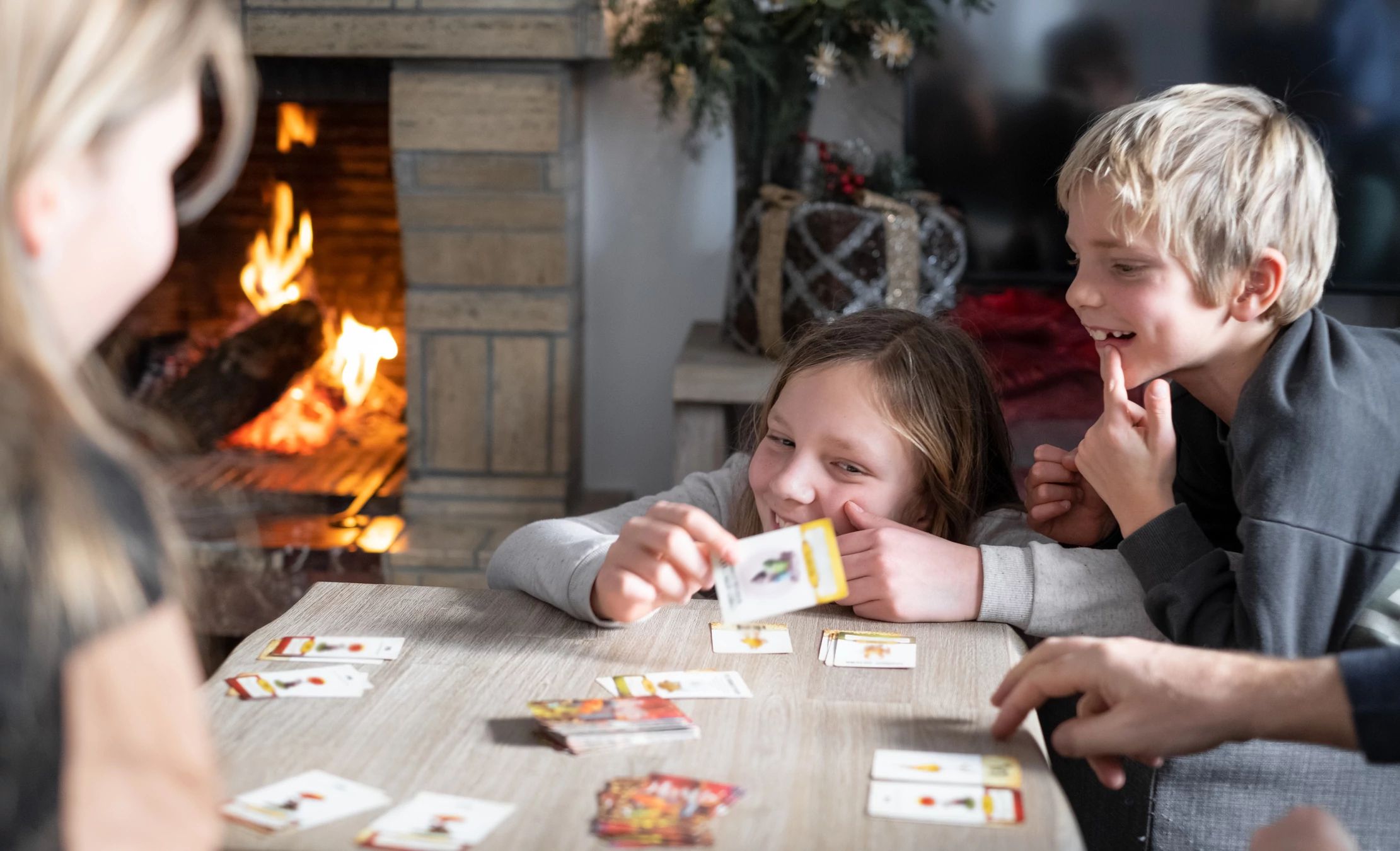 family playing cards together in front of fireplace