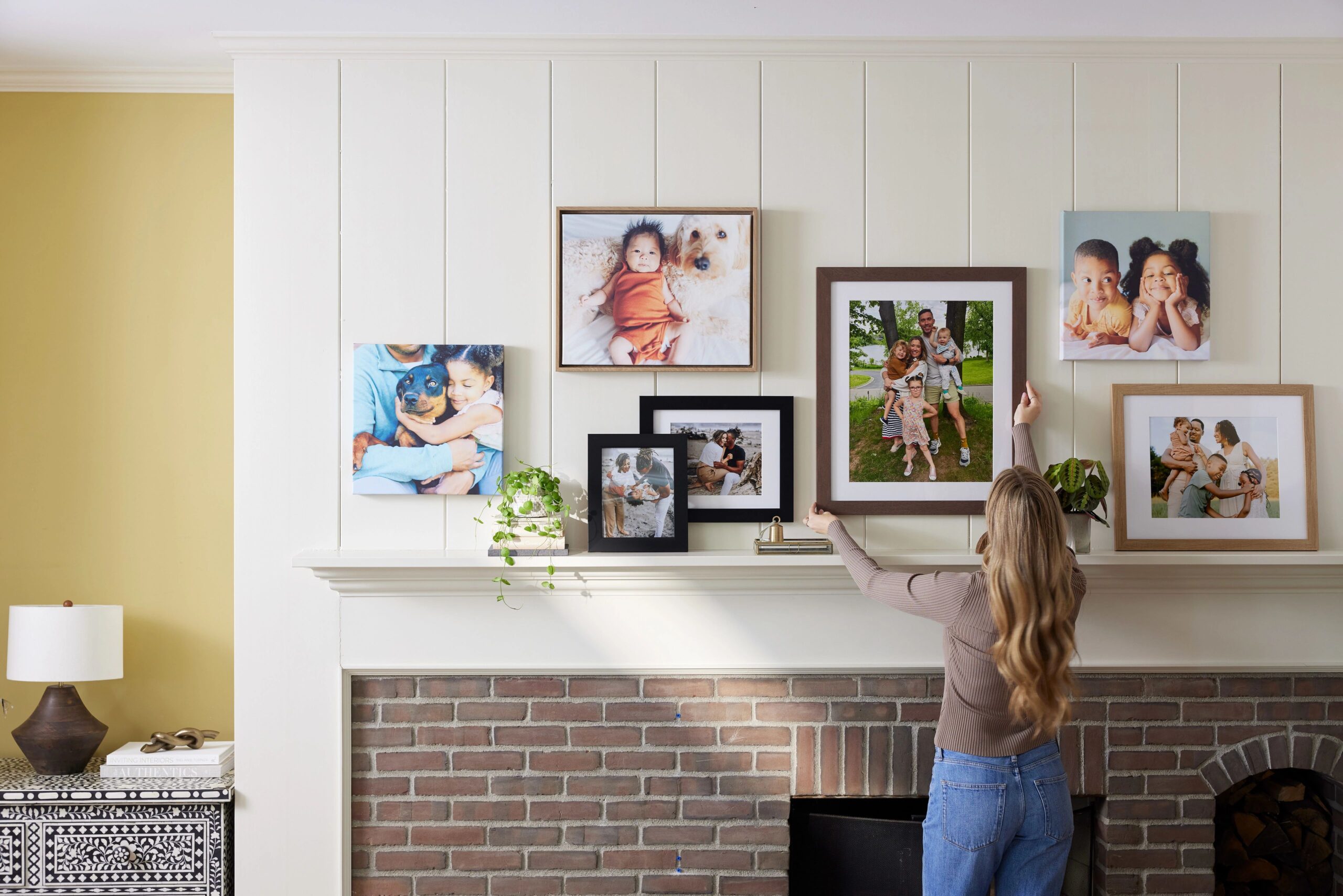 woman hanging canvas prints on gallery wall