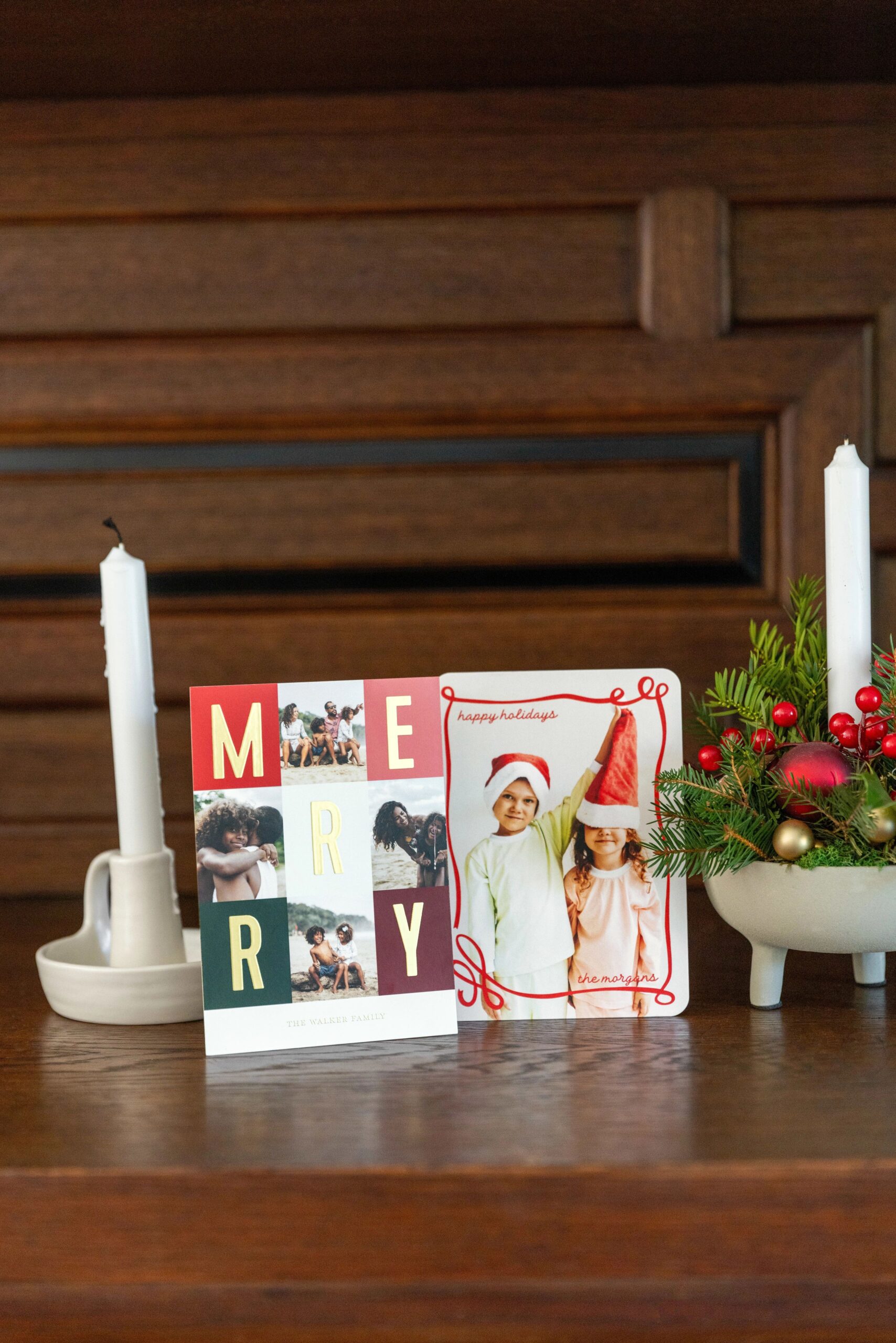 two christmas cards displayed on a mantle 