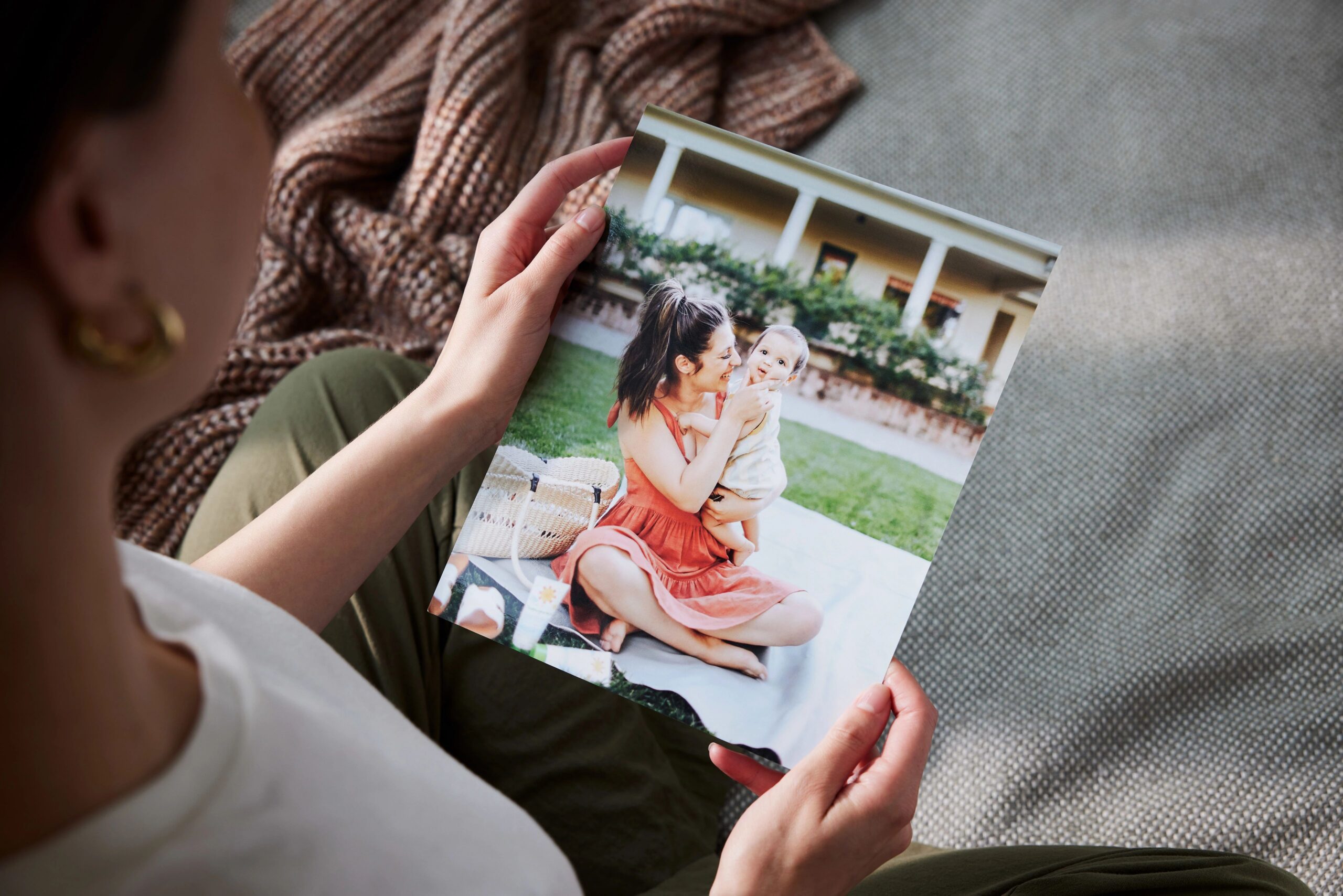 hands holding a large format photo print of mother and baby