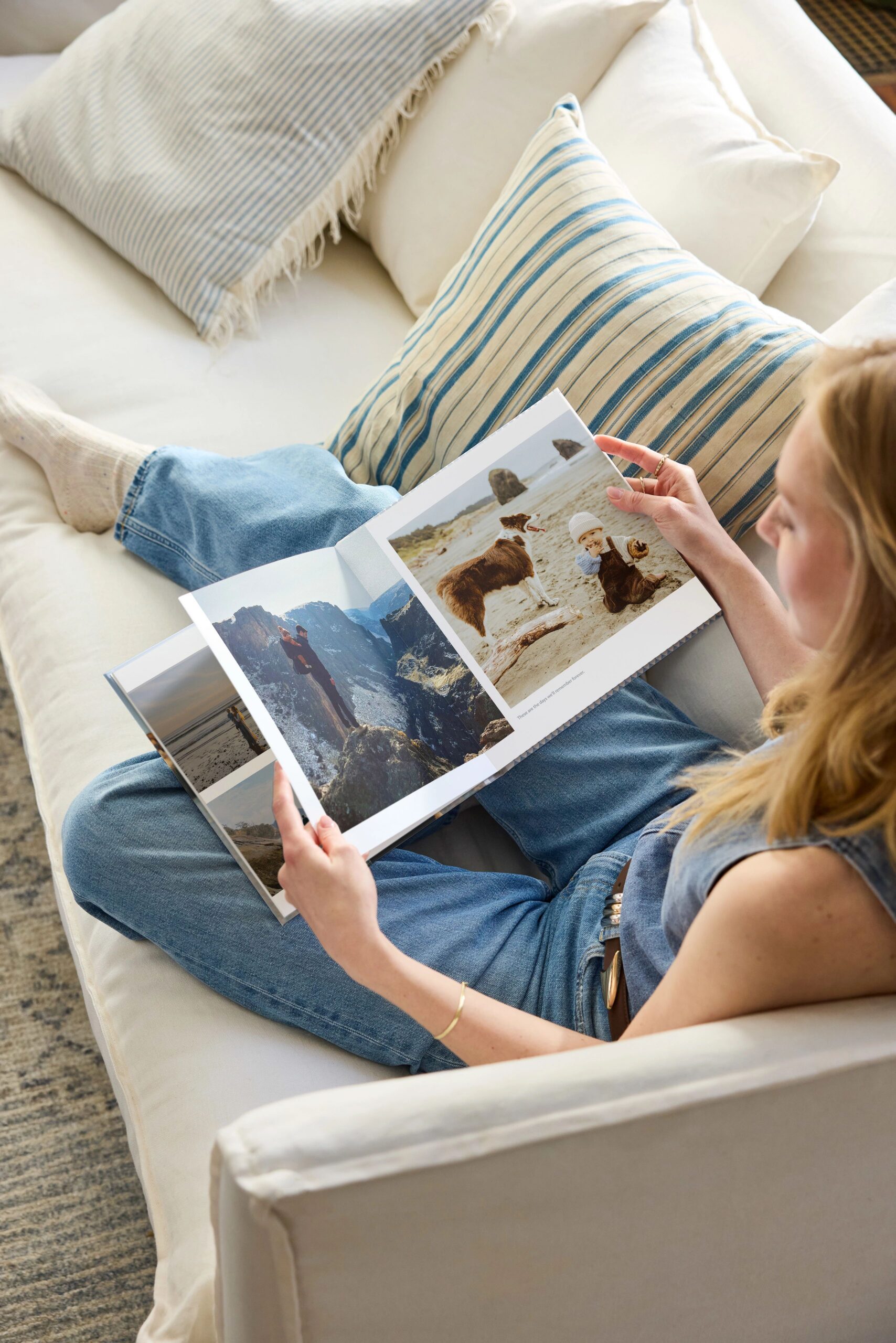 woman on couch flipping through photo book