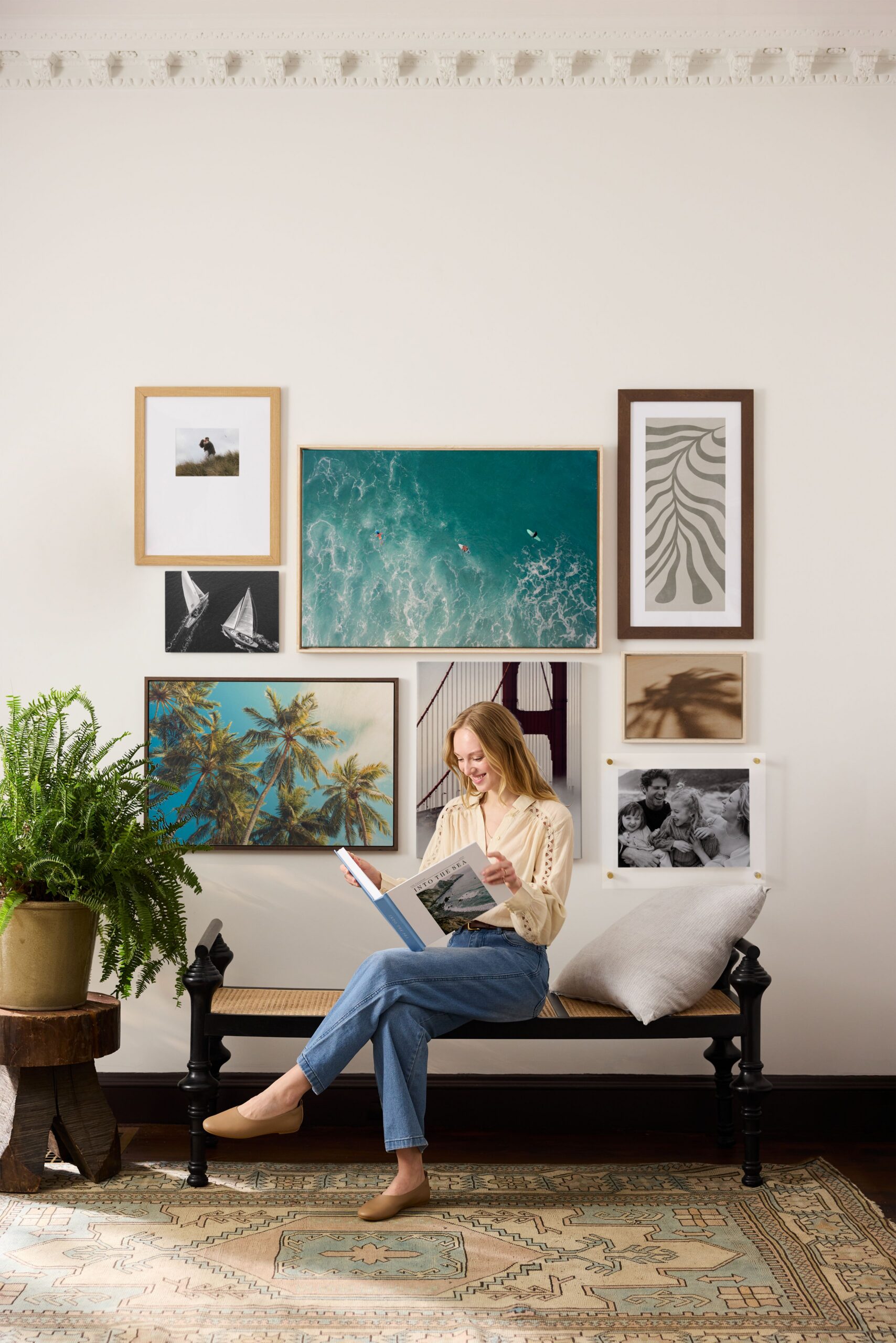 woman holding travel photo book in front of travel gallery wall